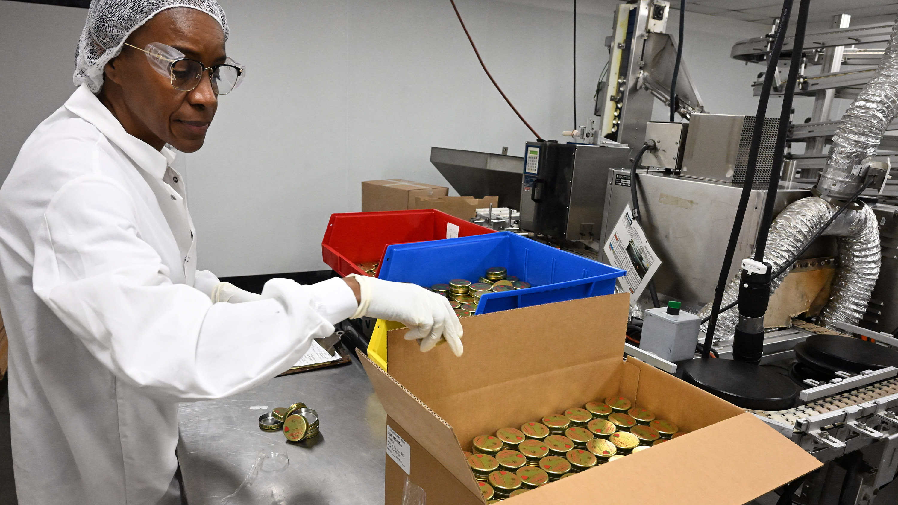 Maria Mosquera boxes completed tins of Smith's Strawberry Lip Balm...