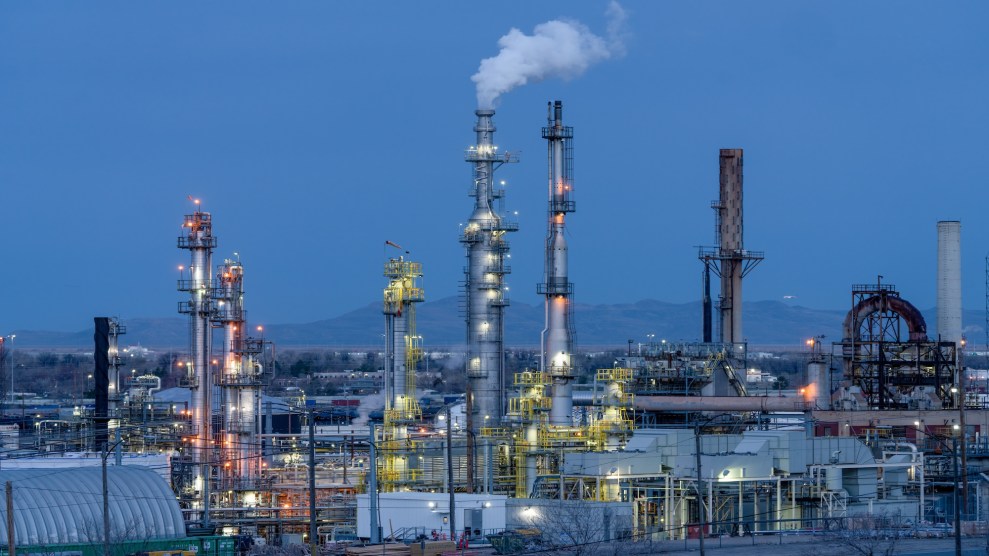 An oil refinery near Salt Lake City glows in the pre-dawn hours; in the background, mountains line the horizon.