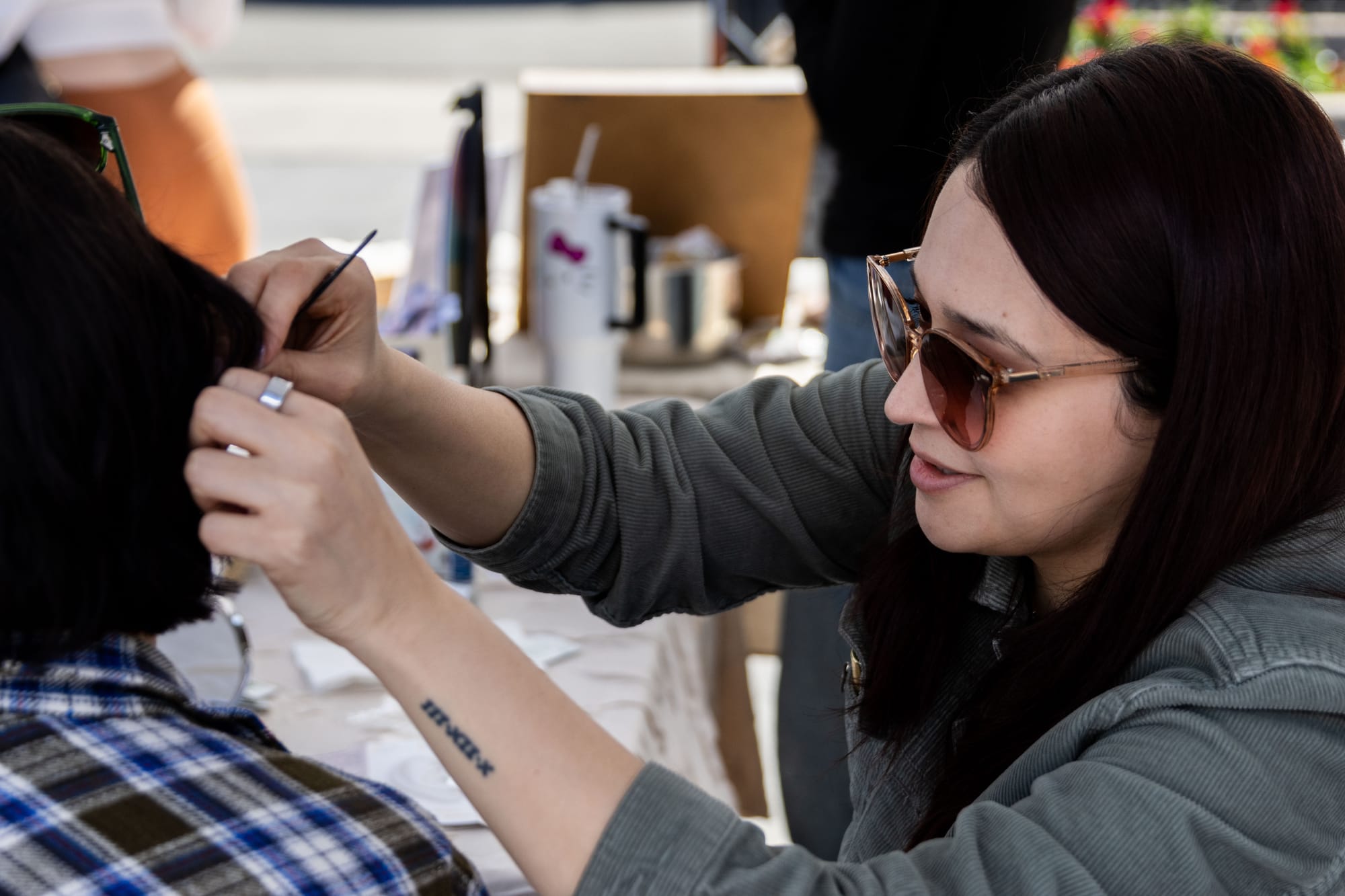 A woman applies an ear seed to someone's ear during an open air market