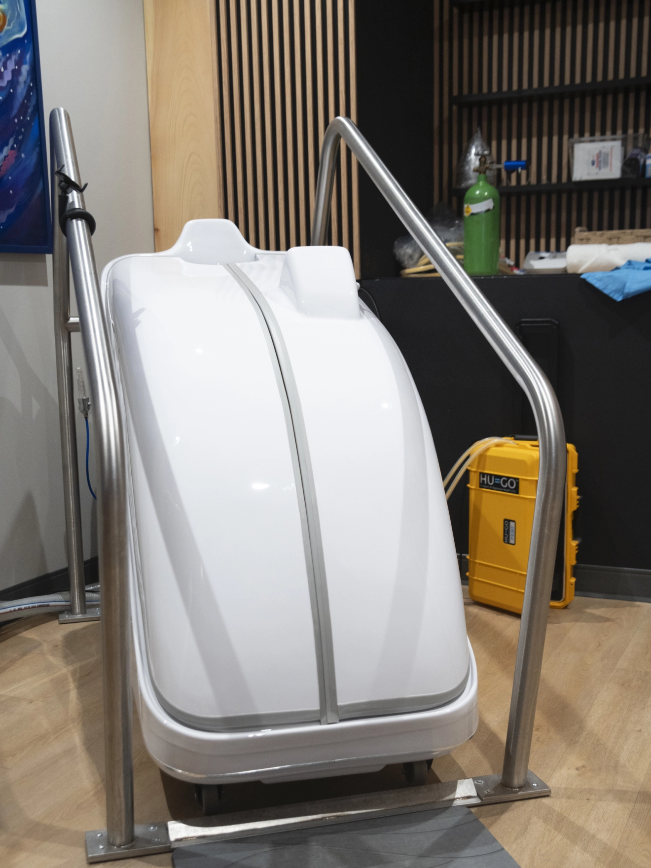 White futuristic chair or pod with metallic handrails in a modern indoor setting.