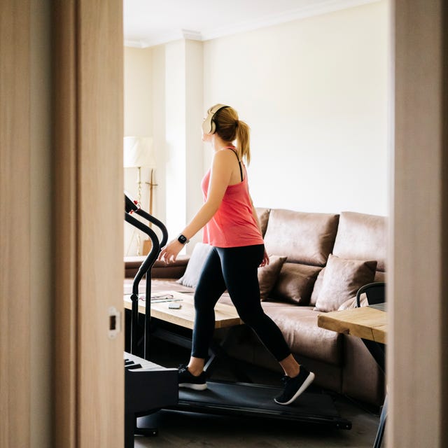 Woman exercising on treadmill at home wearing headphones
