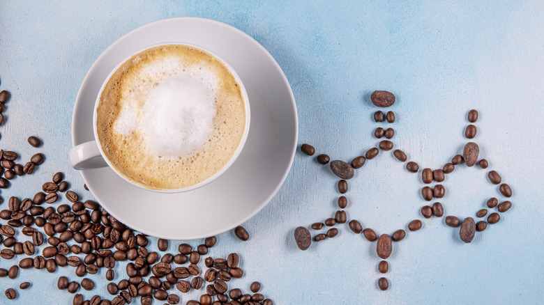 arial view of cappuccino next to beans laid in shape of caffeine molecule