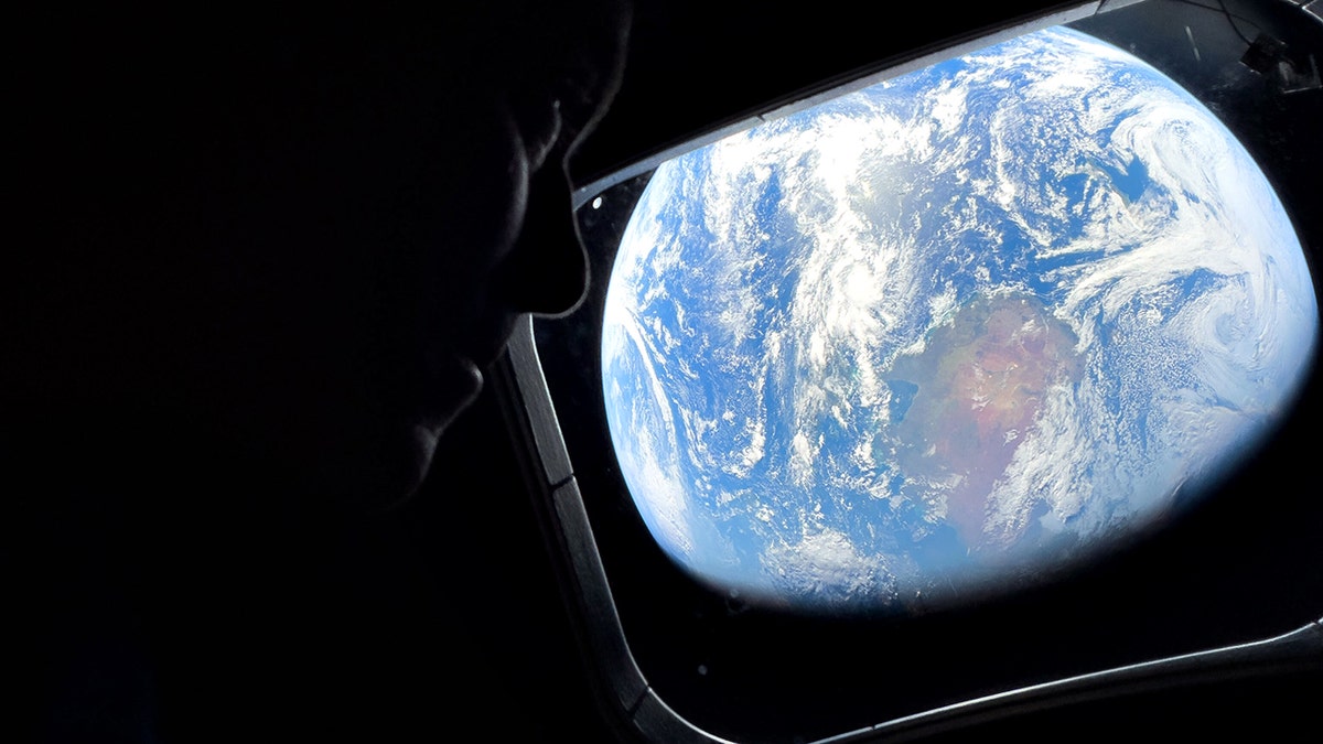 Astronaut Reid Wiseman looking out Orion spacecraft window at Earth.