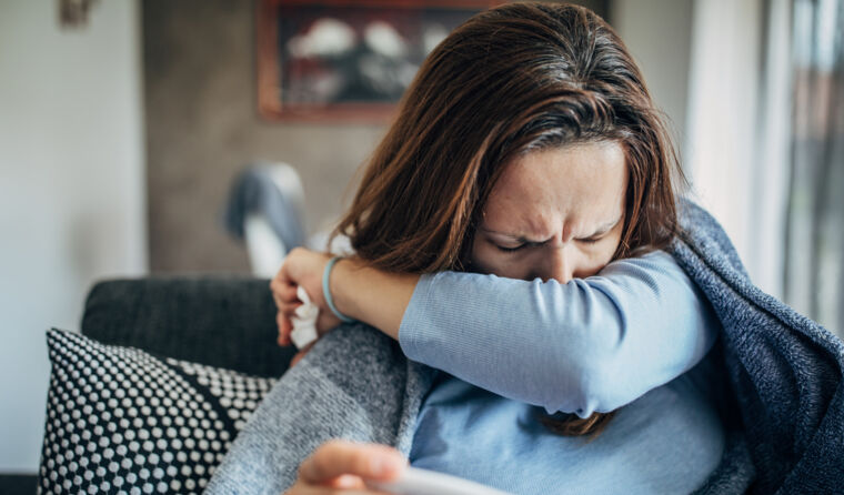 A woman coughing into arm