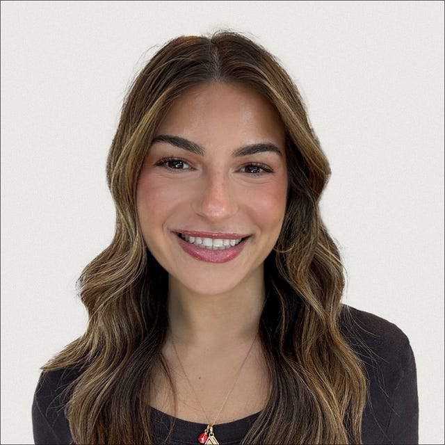 Person with long, wavy hair wearing a black shirt and a necklace.