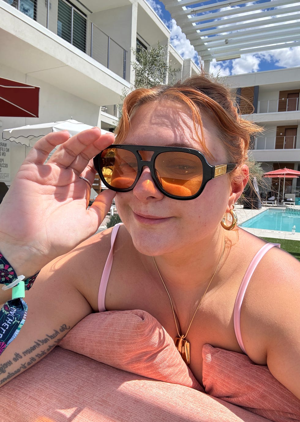 Person lounging by a poolside with sunglasses.
