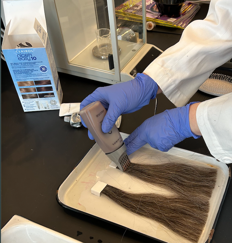Application of hair color on synthetic hair strands.