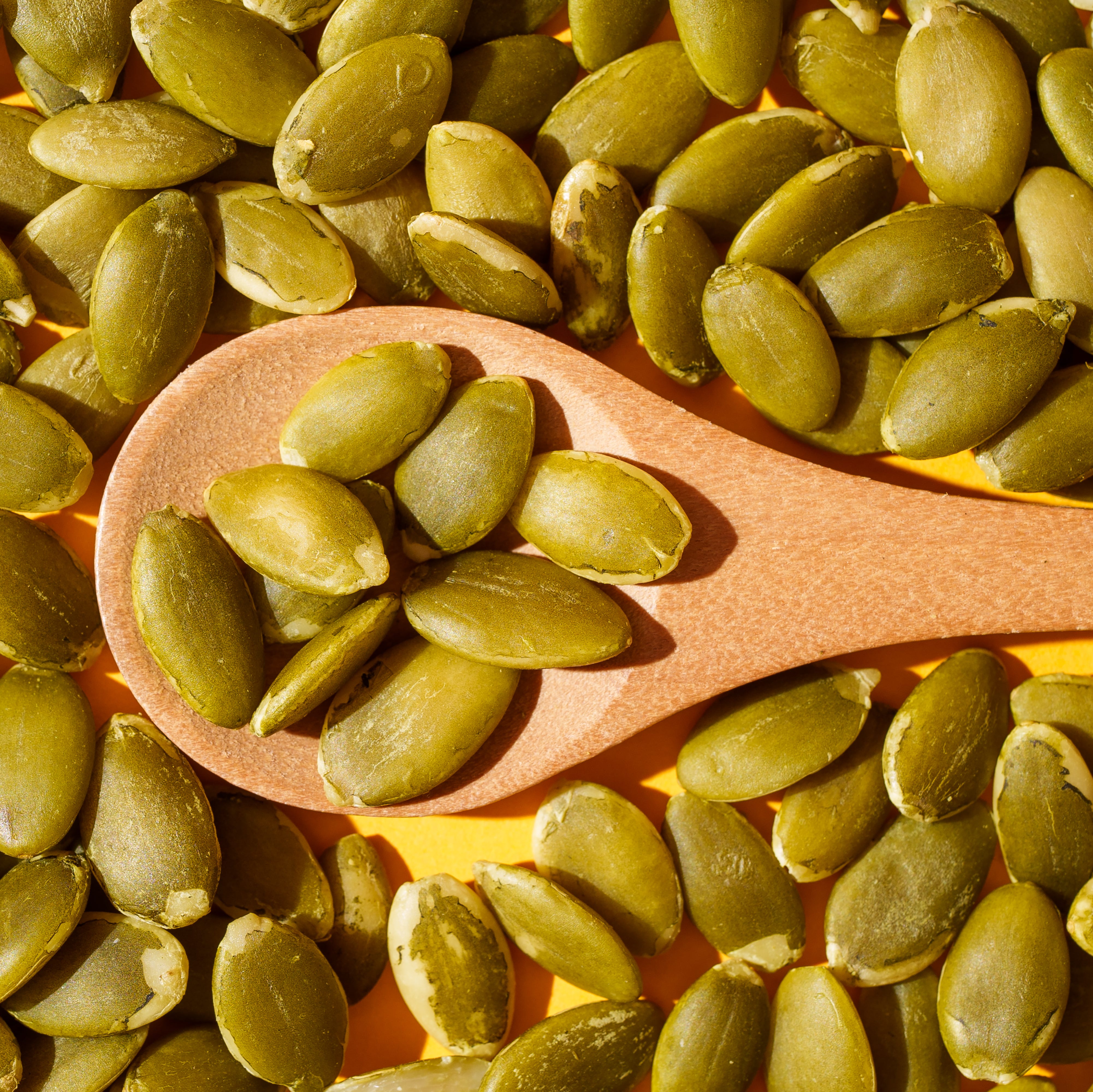 Pumpkin seeds on wooden spoon, healthy eating concept