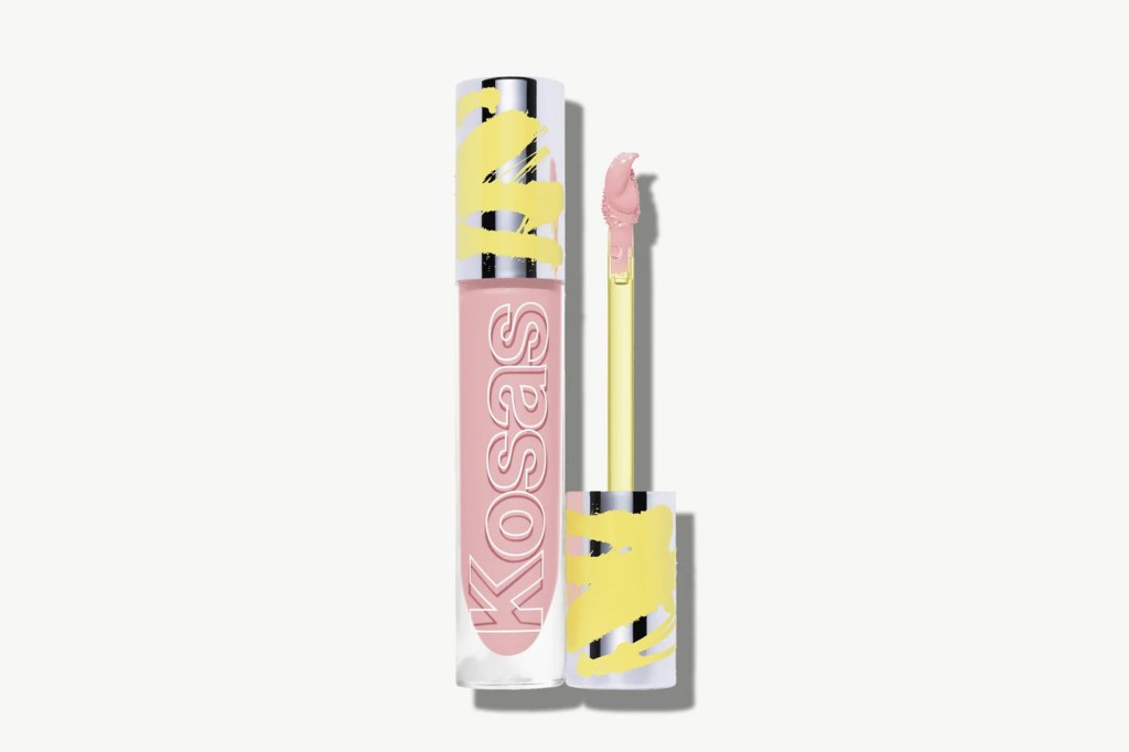A tube of Kosas lip gloss in a light pink shade with a yellow cap, alongside its applicator.