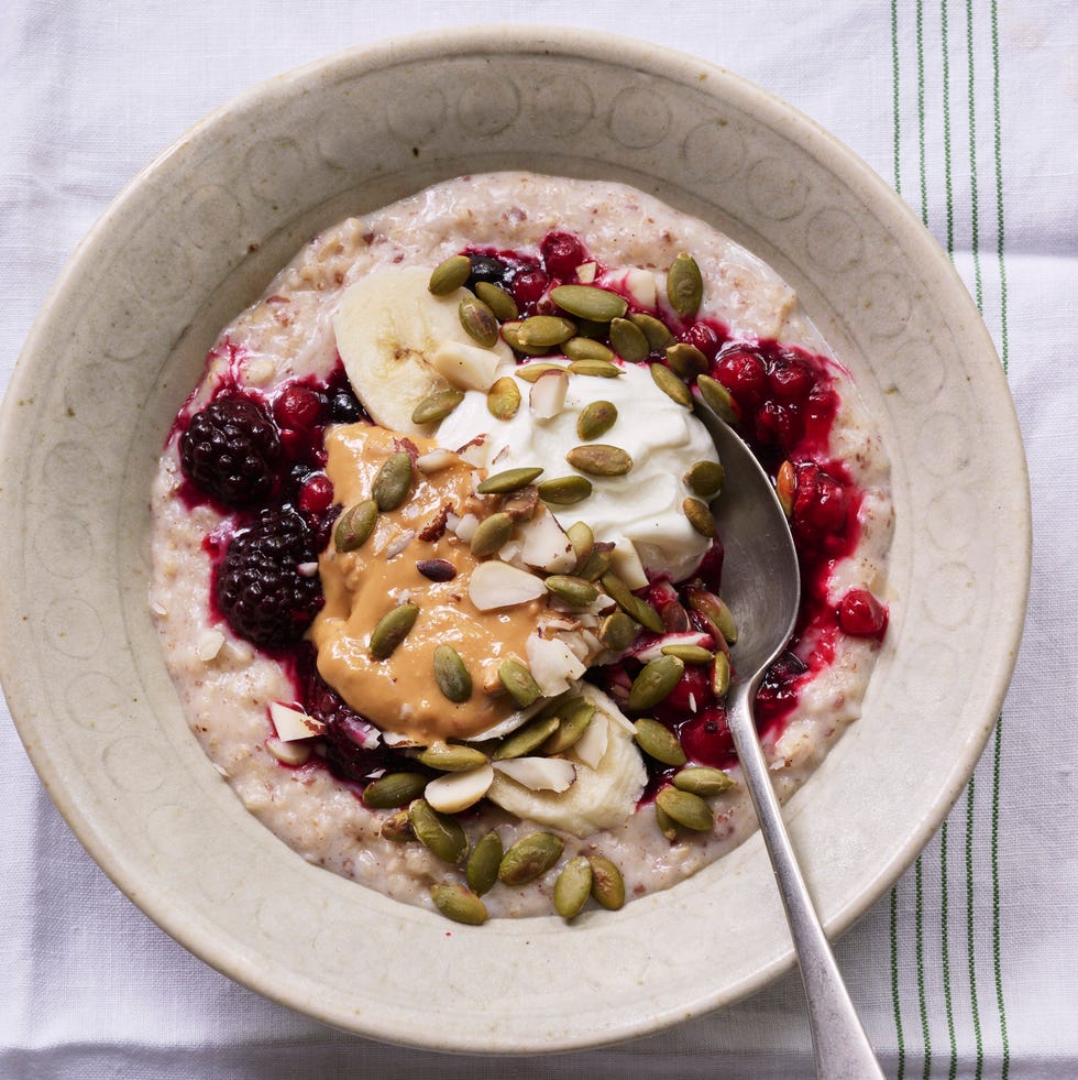 bowl of creamy porridge topped with fruit, nuts and yoghurt for a high protein breakfast