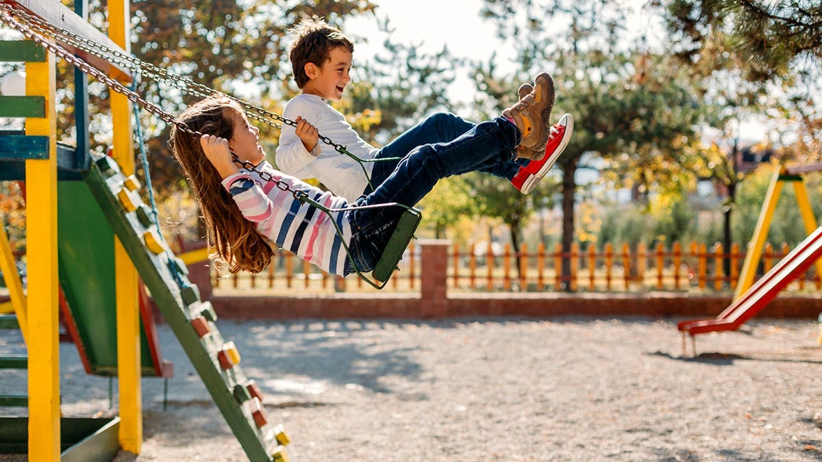 Happy children swinging and playing at a playground