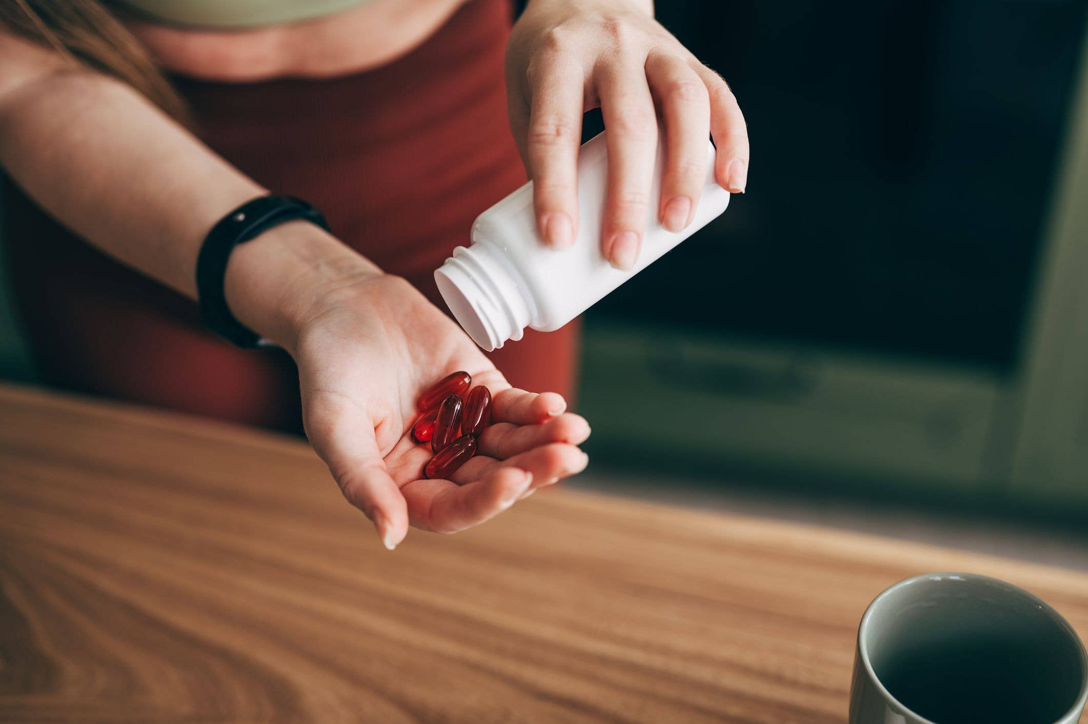 Overhead view of senior Asian woman feeling sick, taking medicines in hand with a glass of water at home. Elderly and healthcare concept