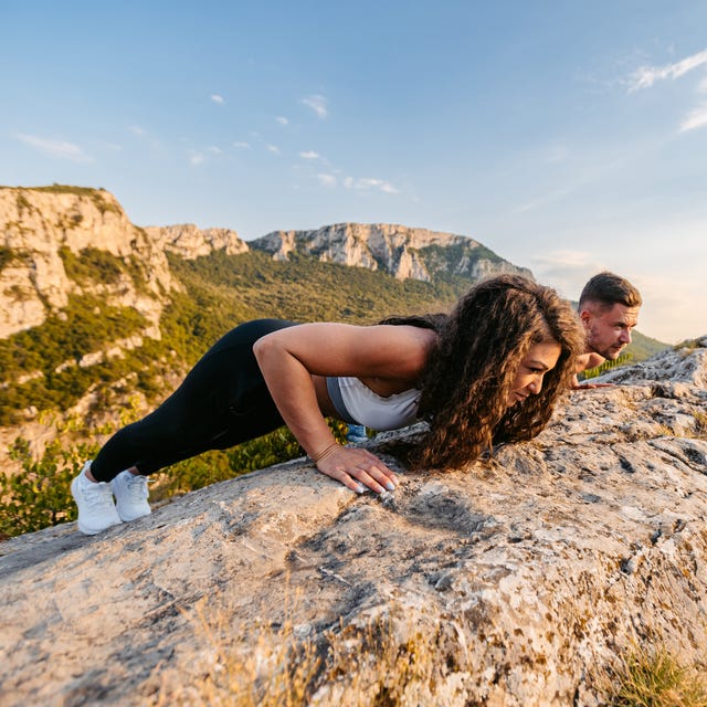Young Couple Doing Push-Ups On Top Of The Mountain