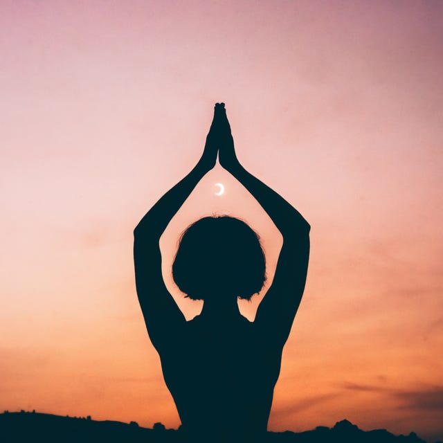 Silhouette of a Person Meditating with Crescent Moon at Sunset
