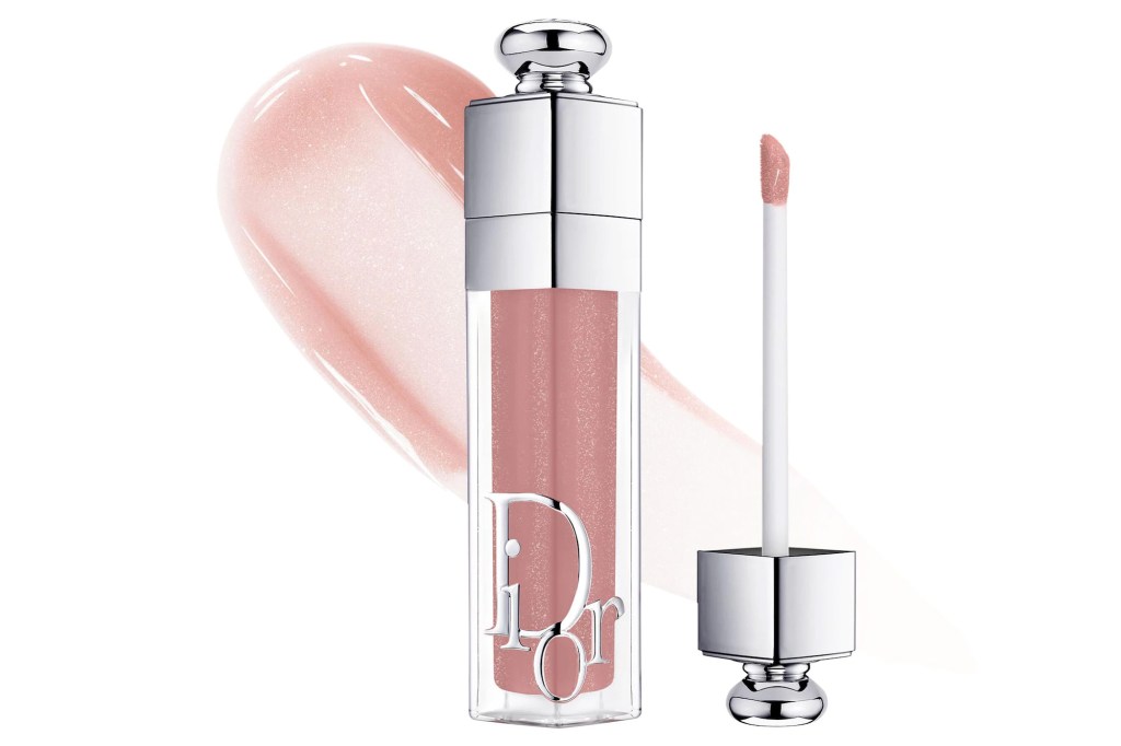 A tube of Dior lip gloss in a light pinkish nude color, with the applicator wand and a swatch of the gloss to its left.
