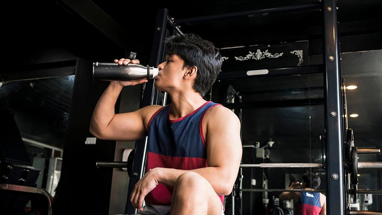 A young, fit man drinking water inside a gym. - MDV Edwards // Shutterstock
