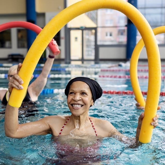 Healthy senior woman doing swim noodle exercises in aerobics pool class