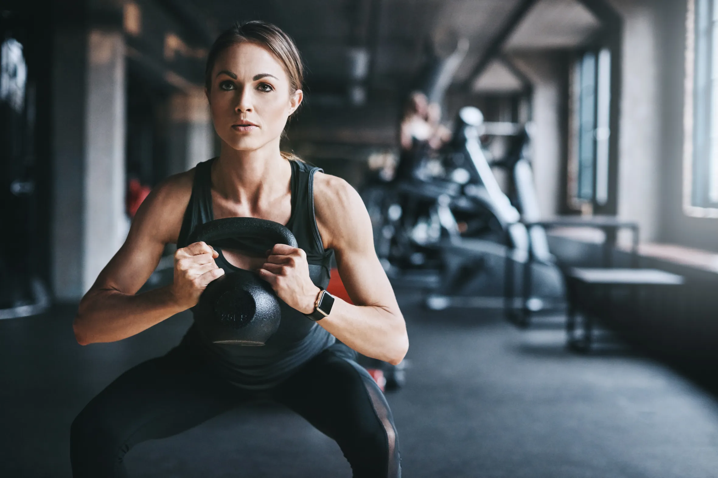 Young woman in a gym working out with a kettlebell.