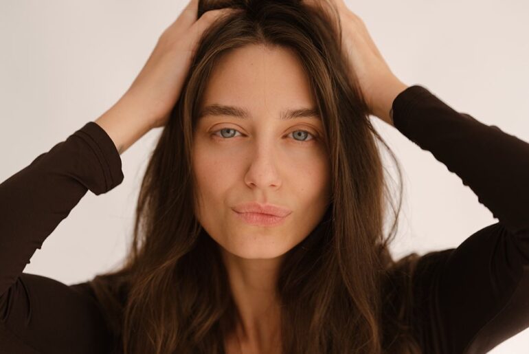 woman in black top touching hair
