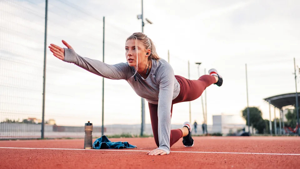 a woman doing the bird dog exercise on a track