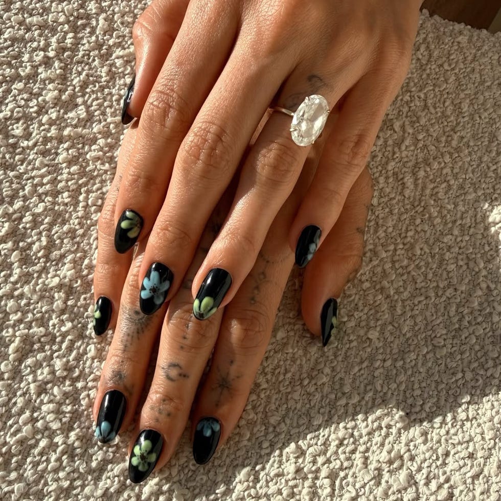 Decorative black nails with floral designs and a ring.