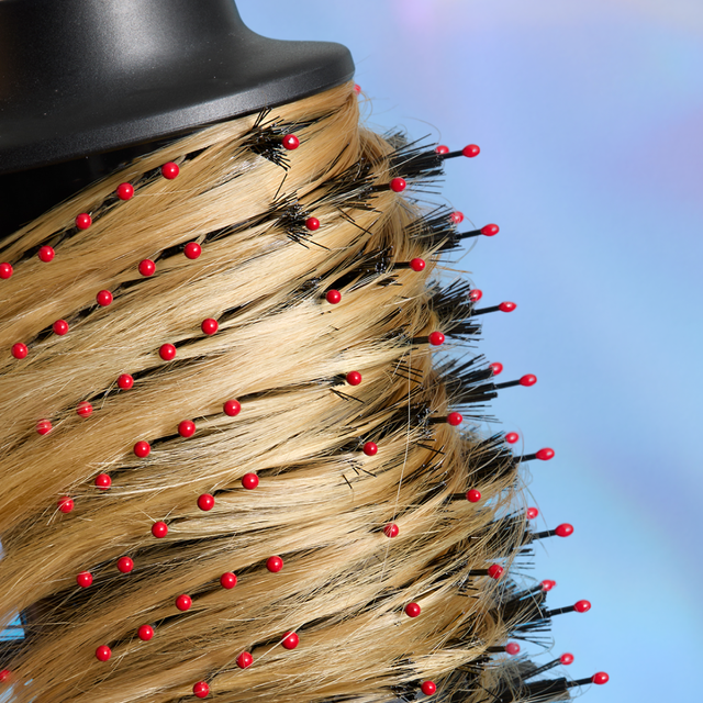 Round brush with synthetic bristles and red tips, used for hairstyling.