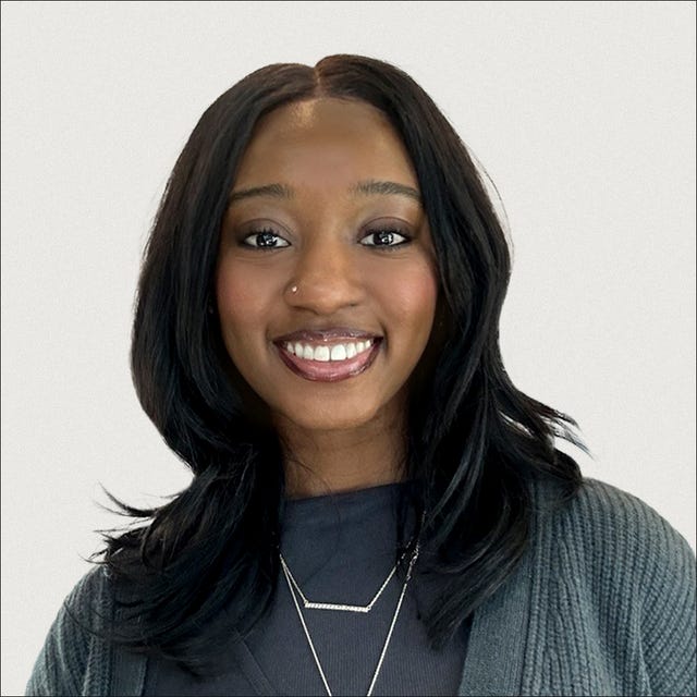 Individual with long, dark hair wearing a textured cardigan and layered necklaces.