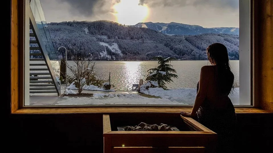 Woman in a spa overlooking a snowy lake and mountains in Austria