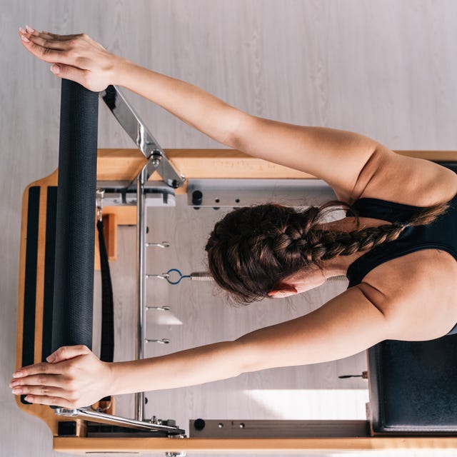 Slender beautiful woman doing Performer Pilates on exercise machines on a sunny day.