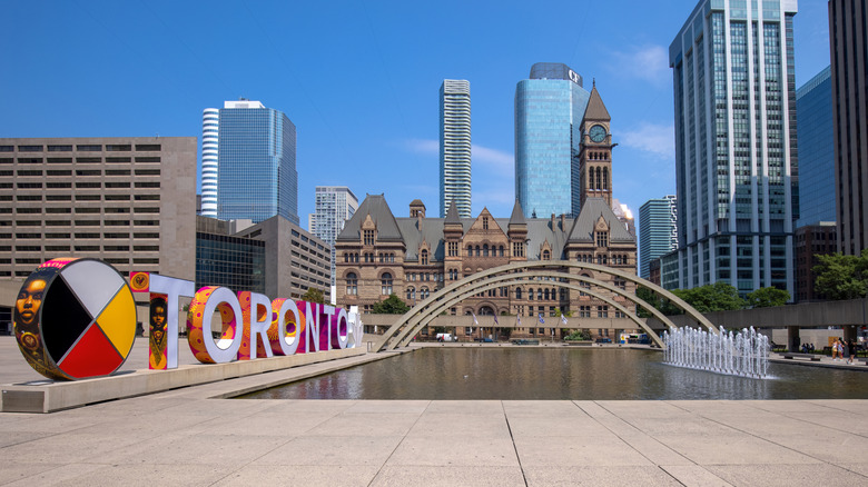 Toronto sign in Nathan Phillips Square with water feature and interesting buildings