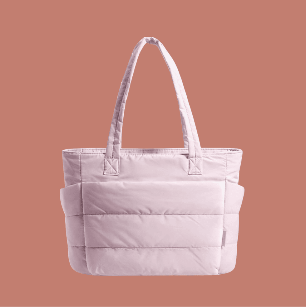 Light pink quilted tote bag with double handles on a muted brown background.