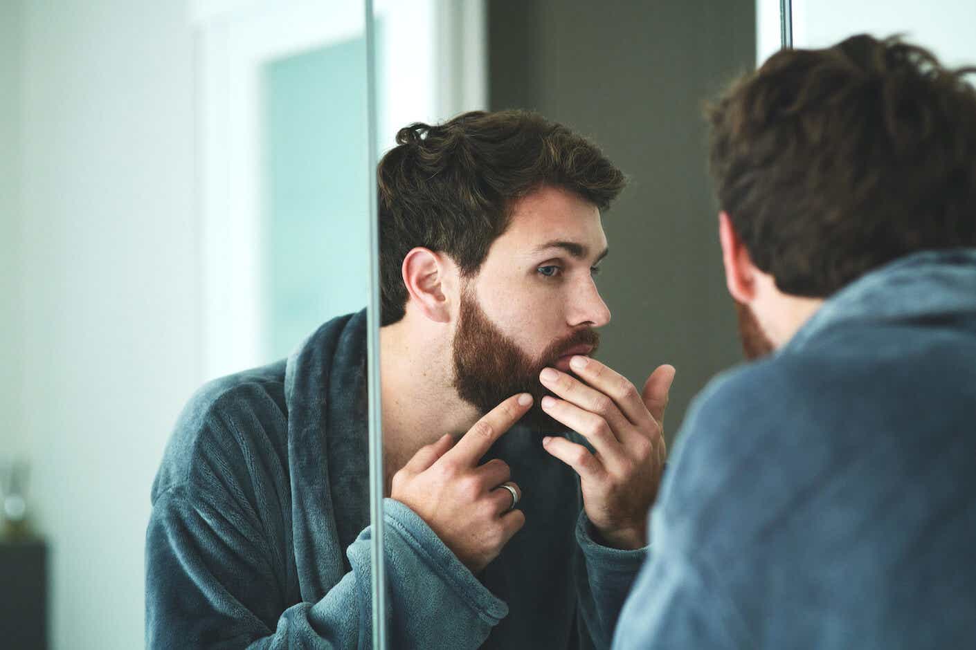 A young man examining his face in the mirror.