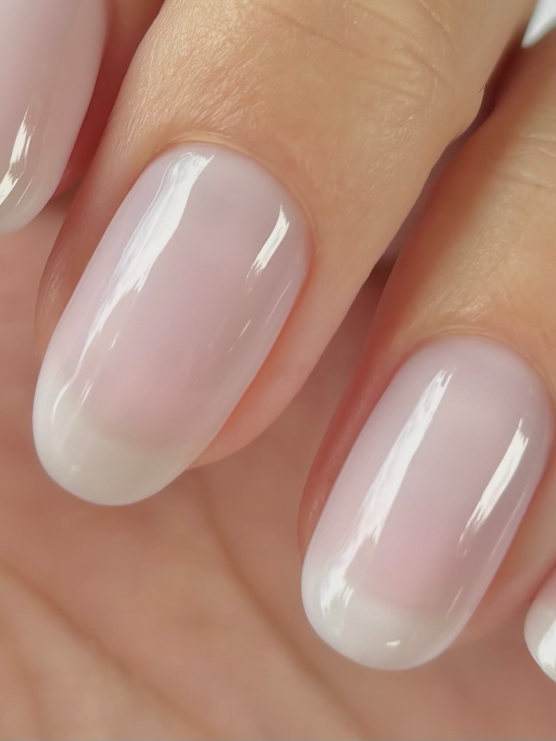 A close-up of a sheer, milky white manicure