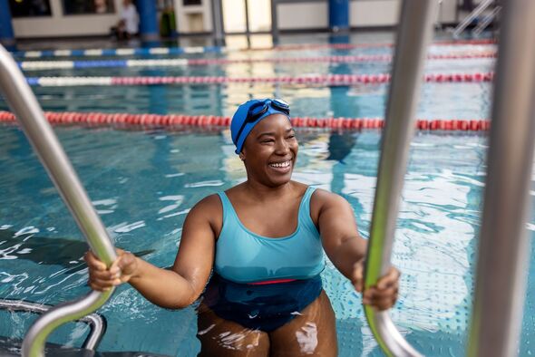 Smiling woman swimmer entering pool Smiling woman swimmer entering pool