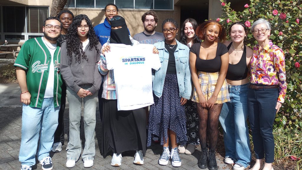 Students hold up a UNCG t-shirt.
