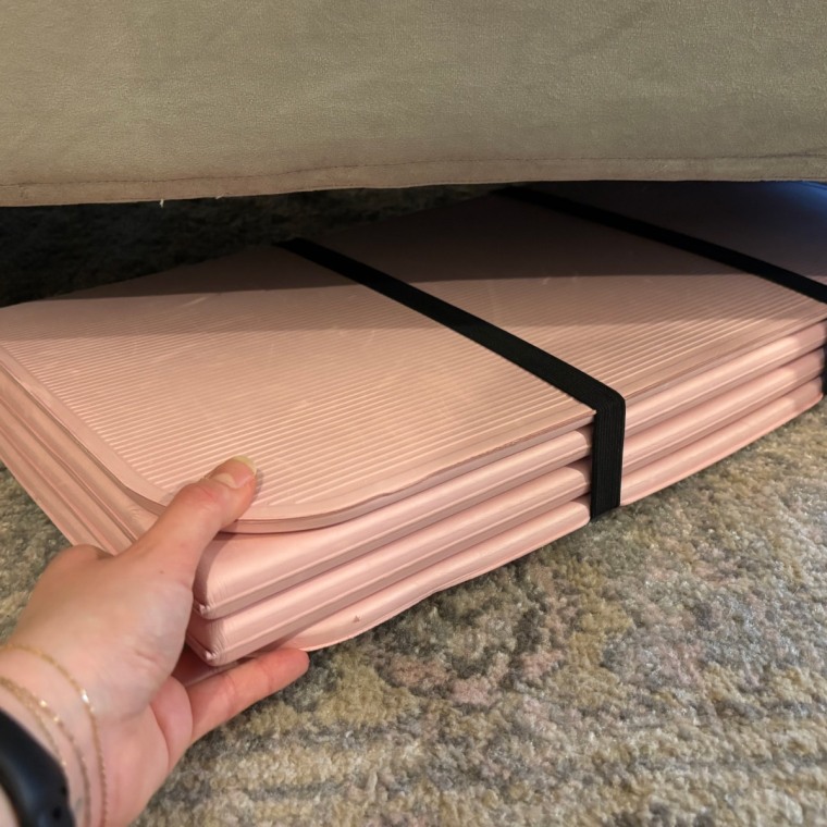 Woman sliding Stakt mat underneath a couch