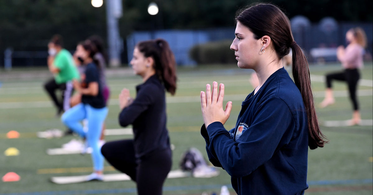 Students practicing yoga, which goes along with the theme of wellness.