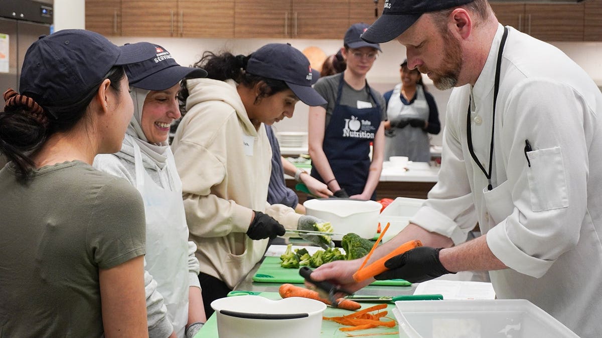 Chief Culinary Officer Brian Hillmer, who oversees the production kitchen at Community Servings, teaching students at Tuft's cooking skills.