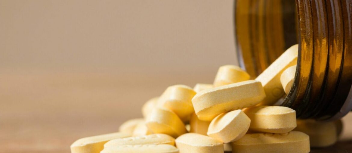 Vitamin tablets spilling out of an open bottle