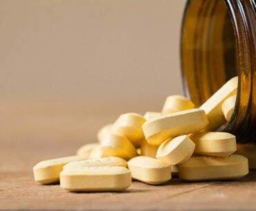 Vitamin tablets spilling out of an open bottle