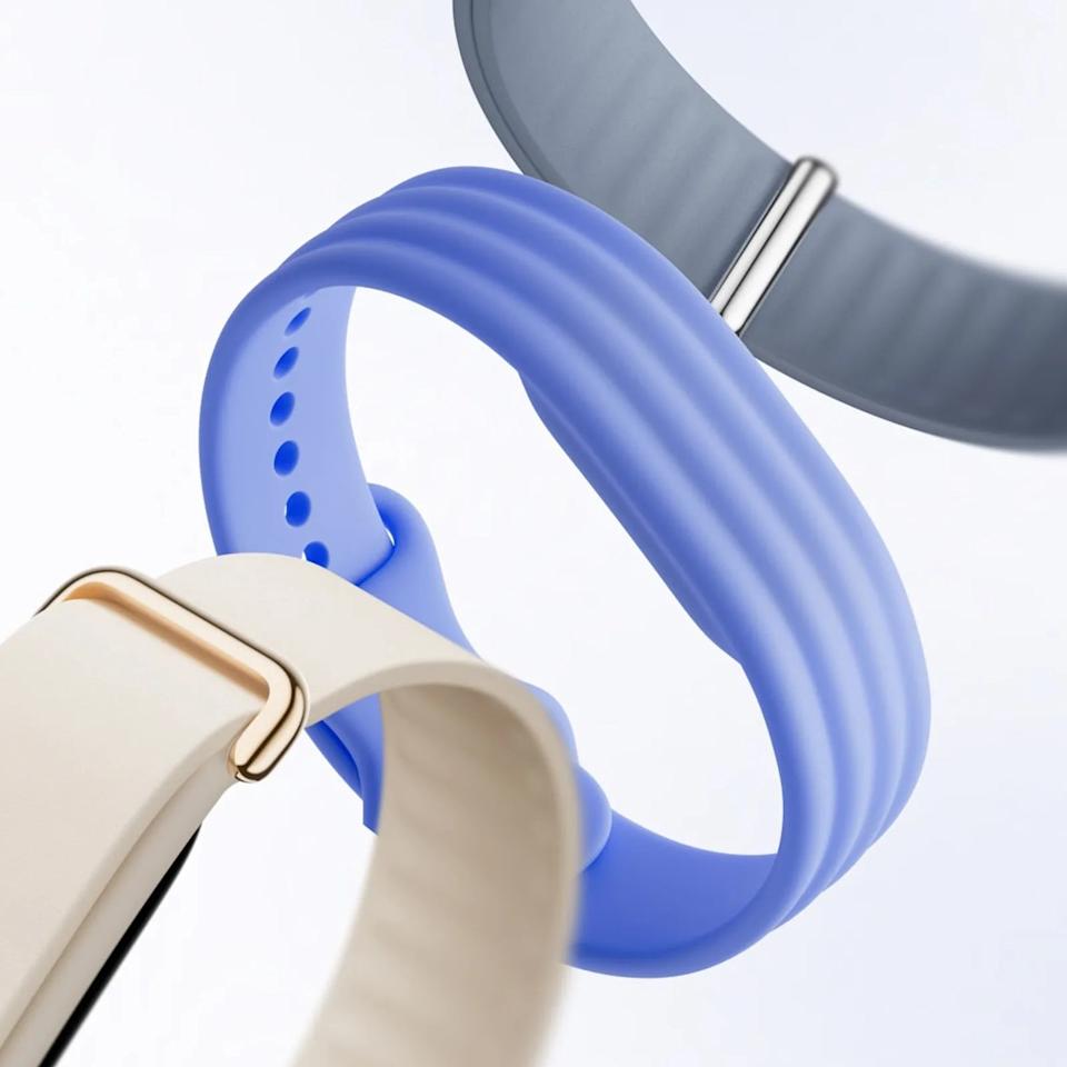 Three close-up silicone watch bands in cream, blue, and gray colors with textured ridges and holes for adjustment.