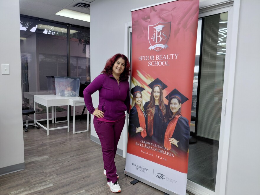A woman wearing a purple sweatshirt and pants poses in front of a 4Four Beauty School sign