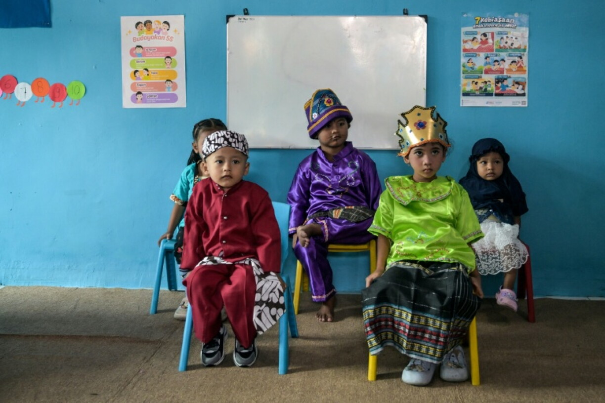 Children wait to receive the measles-rubella vaccine as part of the Indonesian government's drive to combat childhood diseases