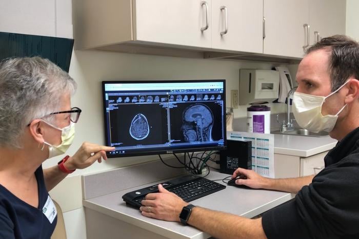 Trial participant Kim Garland (left) reviews a scan with the study’s primary investigator, Tanner Johanns, MD, PhD, a WashU Medicine oncologist