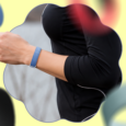Woman wearing a blue Fitbit Air fitness band with colorful bands floating around in the background.