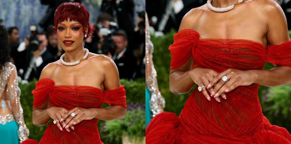 A person wearing a red dress with off-shoulder sleeves and a diamond necklace.