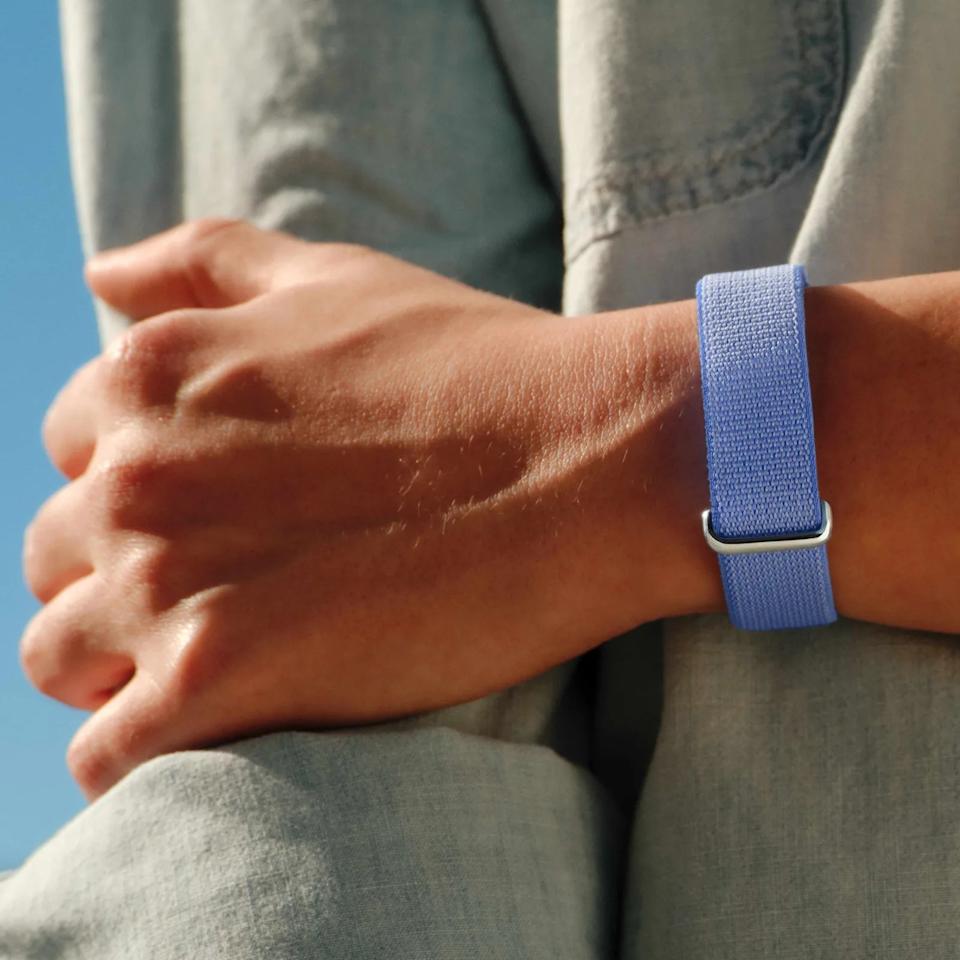 Close-up of a wrist wearing a light blue woven fabric strap with a silver metal buckle.