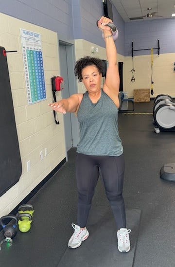 Person lifting a kettlebell in a gym environment.