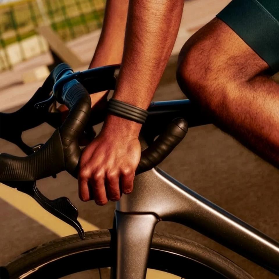 Close-up of a person gripping black drop handlebars on a matte gray road bike.