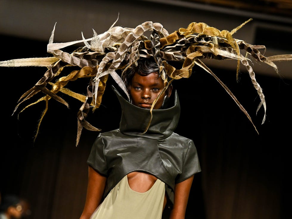 Model showcasing a fashion design with a unique headpiece on a runway.